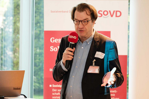 Mann spricht in ein SoVD-Mikrofon. 