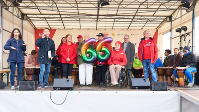 Mehrere Personen auf der Bühne, eine Frau hält Ballons, die die Zahl 66 darstellen. 
