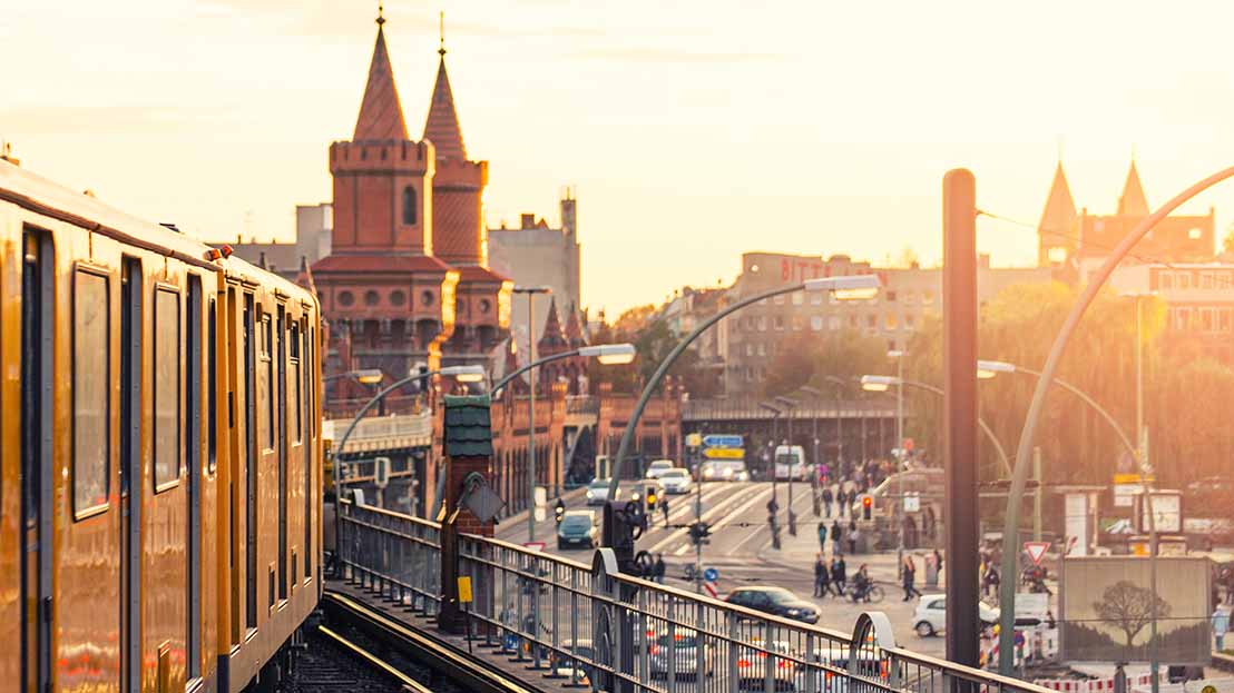 U Bahn fährt über die Oberbaumbrücke in Berlin. Auf der Straße darunter fahren Autos. 